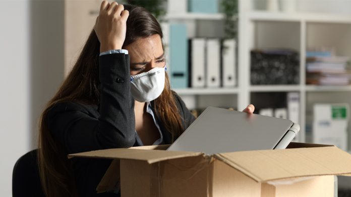 Fired executive with mask packing belongings at night